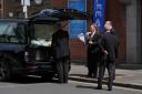 Funeral directors place floral tributes in the hearse (Jonathan Brady/PA)