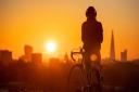 A cyclist watches the sun rise from Primrose Hill, London