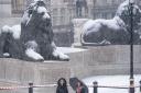 People walk through the snow in Trafalgar Square, central London