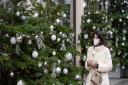 A woman wearing a face mask walks passes a display of Christmas trees outside a shop in central London