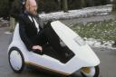 Sir Clive Sinclair demonstrating his C5 electric vehicle, the battery-come-pedal powered trike, at Alexandra Palace in 1985