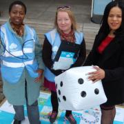 Volunteer Lawrencia Frempong, left, holds an air pollution monitor with volunteer Tiia Haataja, centre, and Cllr Claudia Webbe on the air pollution-themed snakes and ladders game. Picture: Islington Council